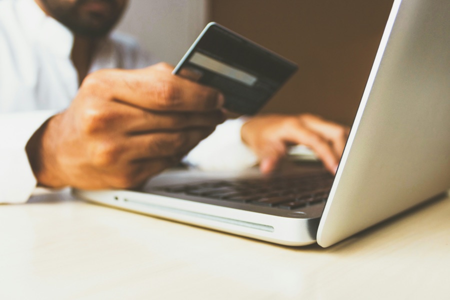 A shopper holding a credit card while typing on a laptop