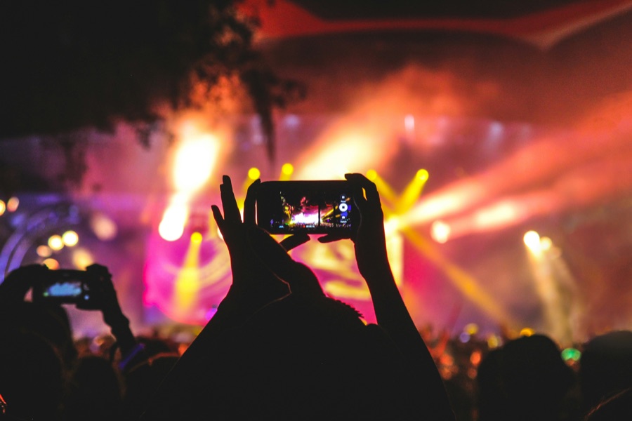 A fan filming a live show on a phone amid stage lights